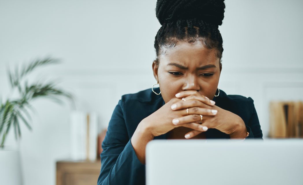 Photo d’une jeune femme d’affaires fronçant les sourcils tout en utilisant un ordinateur portable dans un bureau moderne